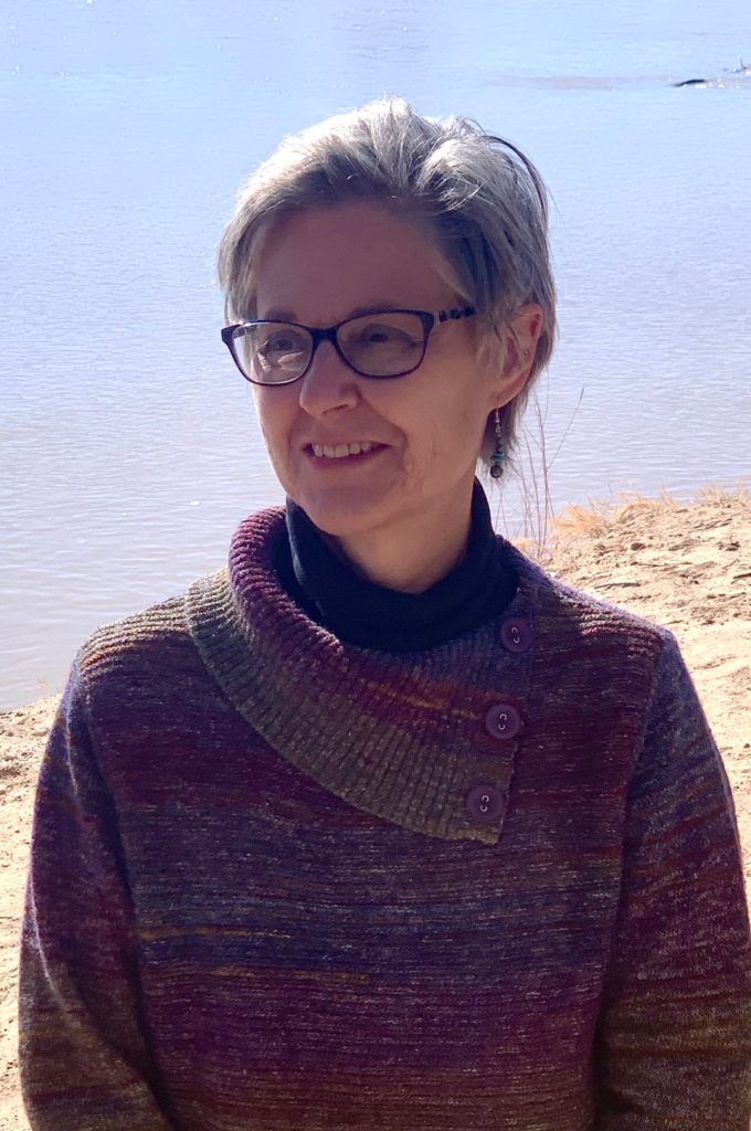 The poet, a woman with graying hair, with the Rio Grande background.